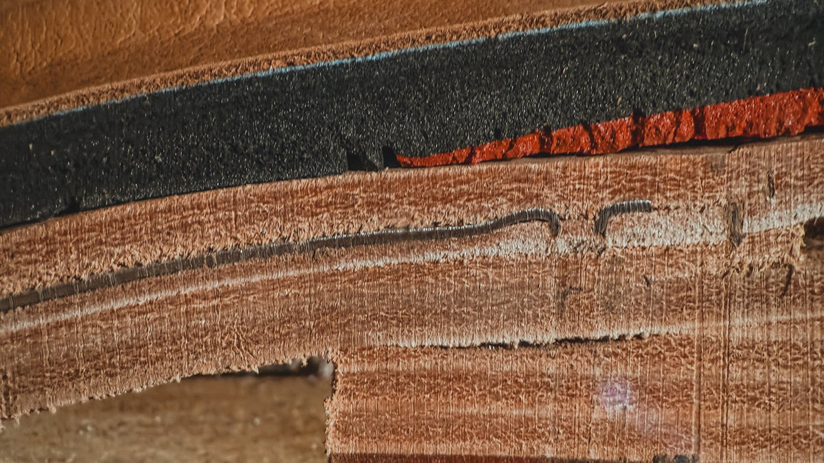 Macro of the cut heel: the comfort insole, with its leather top, black cushioning and red gel, sitting on the thick vegetable-tanned leather insole